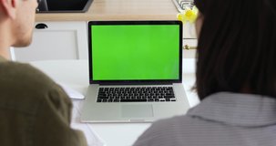 Back view of creative millennial couple working together or watching video on Macbook pro laptop in kitchen. Business man and woman working from home, computer with green screen. Quarantine, COVID-19