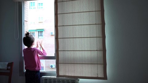 Girl in Spain clapping in the window in support of people who fight against the coronavirus