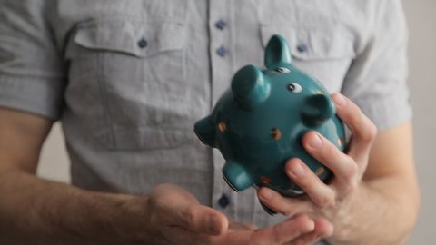 Man empties a piggy bank, last few coins falls. Last money, end of savings, crisis, bankruptcy