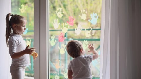 Children paint with palms on the window. Quarantine Stay at home
