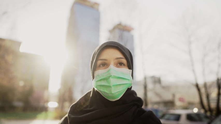 Female Muslim with protective surgical mask.Hijab woman wearing mask in the city.Coronavirus COVID-19 pandemic lifestyle in Islamic country culture.Spiritual praying concerned person.Faith challenge Royalty-Free Stock Footage #1049923015