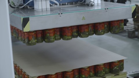 Preserving Tomatoes and cucumbers. Close up of Glass jars with Tomatoes and cucumbers in factory storage