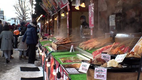 SAPPORO, HOKKAIDO, JAPAN - 11 FEB 2020 : View of street food and drink stalls at Sapporo Snow Festival. One of Japan's most popular winter events. Various kinds of traditional Japanese food are sold.