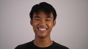 The Asian boy laughing and looks happy with white background