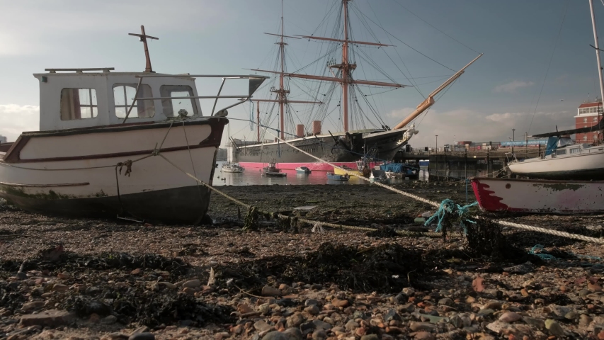 Camera rises from beside small boat to reveal HMS Warrior in Portsmouth Historic Dockyard
