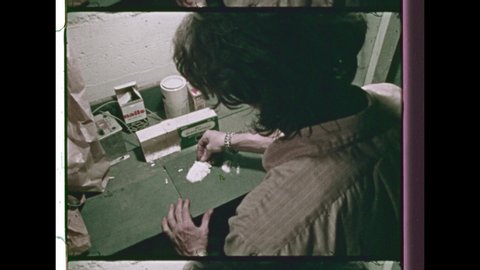 1970's A Drug Dealer prepares illegal Methamphetamine in Suburban Garage. Close-Up of a Razor cutting the Drugs into Pills. 4K Overscan of 16mm Film Showing Frame Lines & Sprocket Hole 