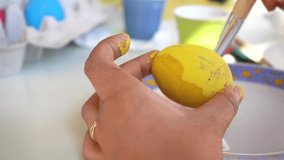 A teenager paints an Easter egg with a brush in yellow, in view of the approaching Easter. video shot in 4k