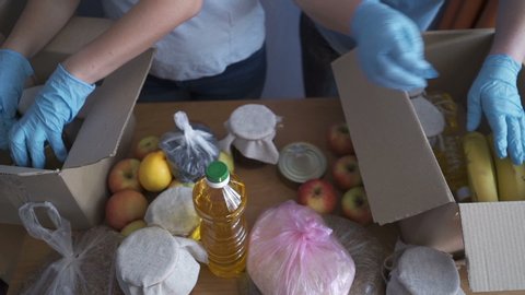 Volunteers in protective suits pack products. Food delivery services during coronavirus pandemic for working from home and social distancing. Shopping online.