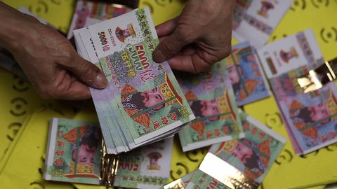 Hands counting hell money or joss paper for the dead in China