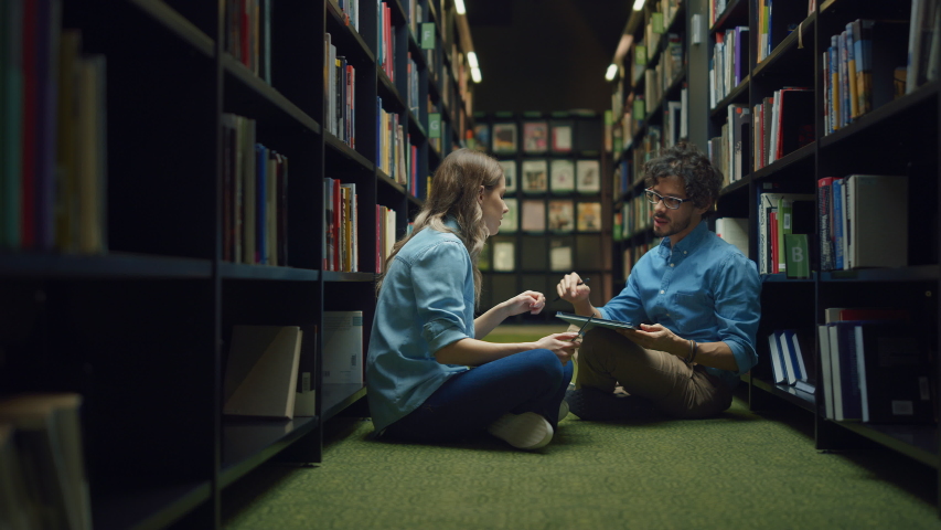 University Library Study: Smart Caucasian Girl Sitting and Talented Hispanic Boy Sitting Cross-Legged On the Floor, Talk, Use Laptops, Collaborate and Discuss Paper, Study and Prepare for Exams Royalty-Free Stock Footage #1049967709