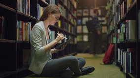 University Library: Beautiful Caucasian Girl Sitting On the Floor, Uses Digital Tablet Computer and Writes Notes for the Paper, Study for Class Assignment. Diverse Group of Students Learning - Powered by Shutterstock - Get 15% off with code: PIKWIZARD15
