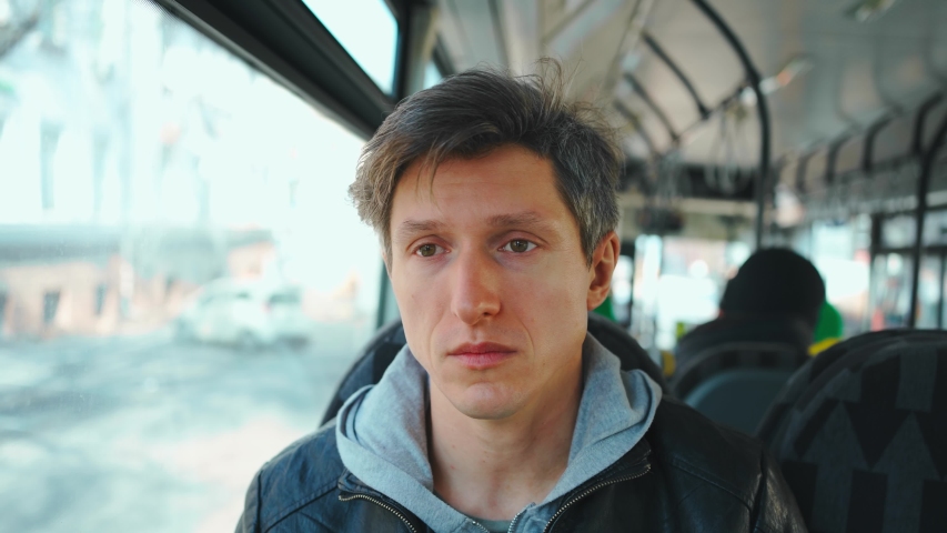 middle aged european man looking sick while sitting in city bus. sick male in public transport without protective mask looks straight at camera.