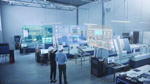 Industry 4.0 Factory: Two Engineers Uses Digital Tablet Computer with Augmented Reality Software to Connect with CNC Machinery, Robot Arm and Visualize Maintenance and Diagnostics of the Equipment