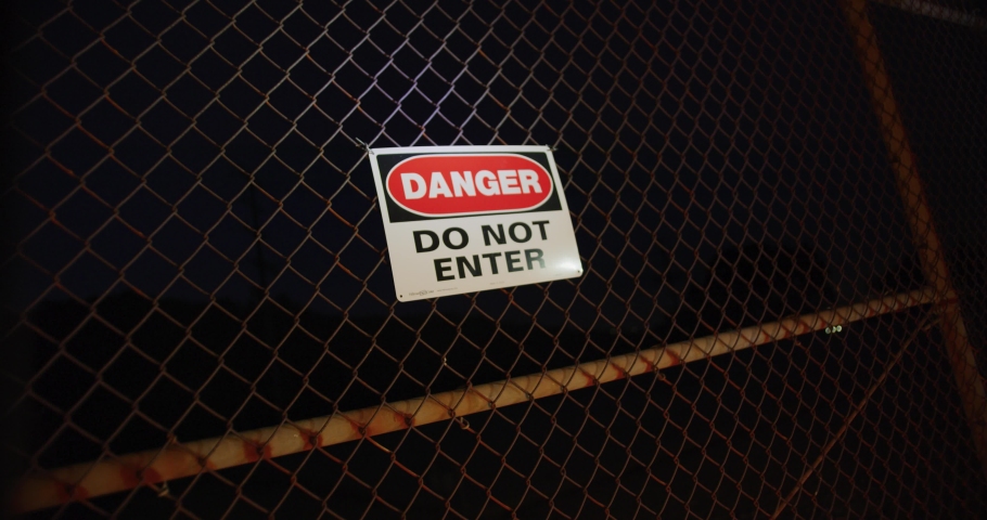 Danger Do Not Enter sign at fence at night