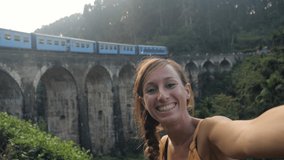 Selfie of young woman traveling in Sri Lanka and taking video call while train passing on background. Communication connection online sharing on mobile phone concept  SLOW MOTION- 