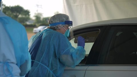 CIRCA 2020 - Covid-19 coronavirus patients are tested at a drive thru clinic. Gowns, masks and test kits shown.
