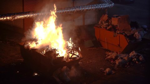 Trash cans burn in the city at night