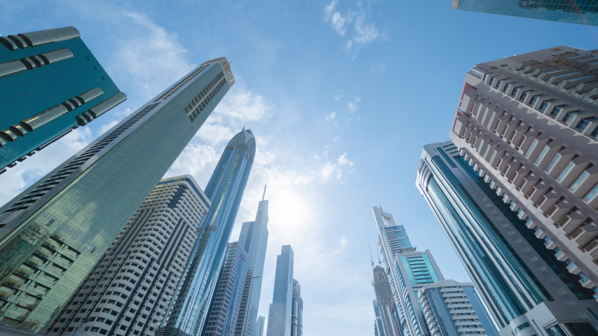 Time lapse of clouds. Pattern of office buildings windows. Glass architecture facade design with reflection in urban city, Downtown Dubai. Urban city in financial district with blue sky.