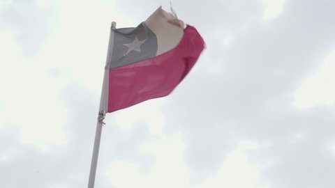 Old damaged waving Chile National flag in a cloudy day. Handheld slow motion real live action footage.