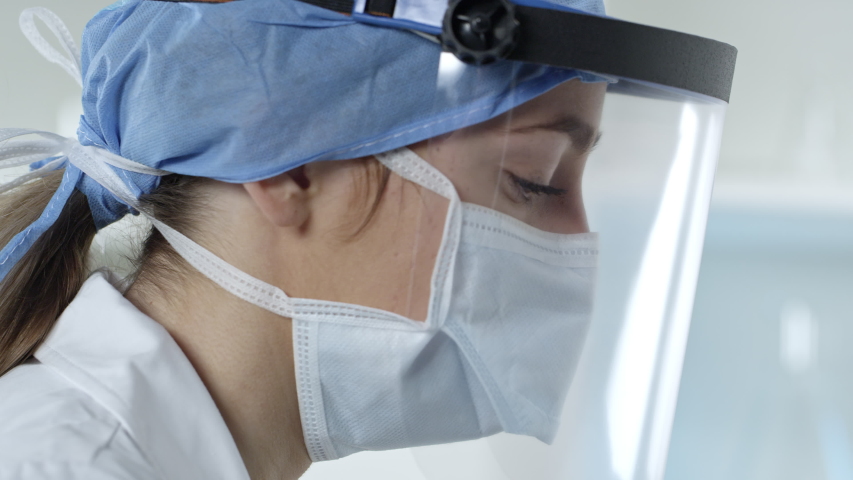 Nurse working on coronavirus test kits in medical lab wearing face shield and mask. | Shutterstock HD Video #1049989783