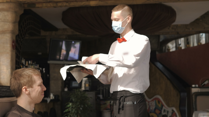 A European-looking waiter in a medical mask serves Latte coffee Royalty-Free Stock Footage #1050001837