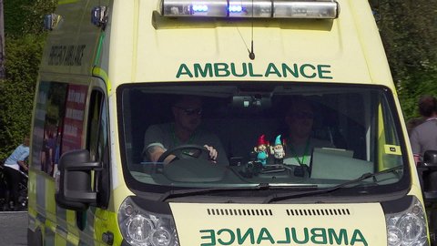 WIRRAL, MERSEYSIDE/ENGLAND - SEPTEMBER 11, 2019: English ambulance drives past with warning signs on side of the vehicle in England during a road cycle race.