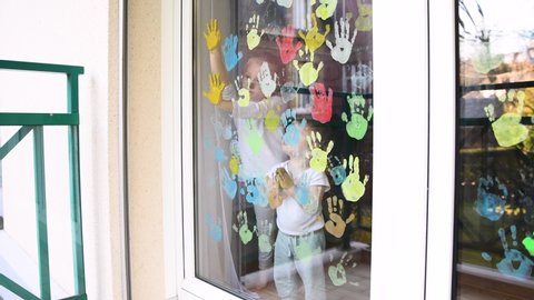 The kids paint with palms on the window. Quarantine