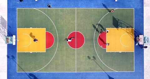 Aerial top down view on colourful basketball court with a group of player on one side and one player being photographed on another side at famous Choi Hung Estate in Hong Kong 