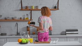 Smiling woman dancing with fresh vegetables in kitchen