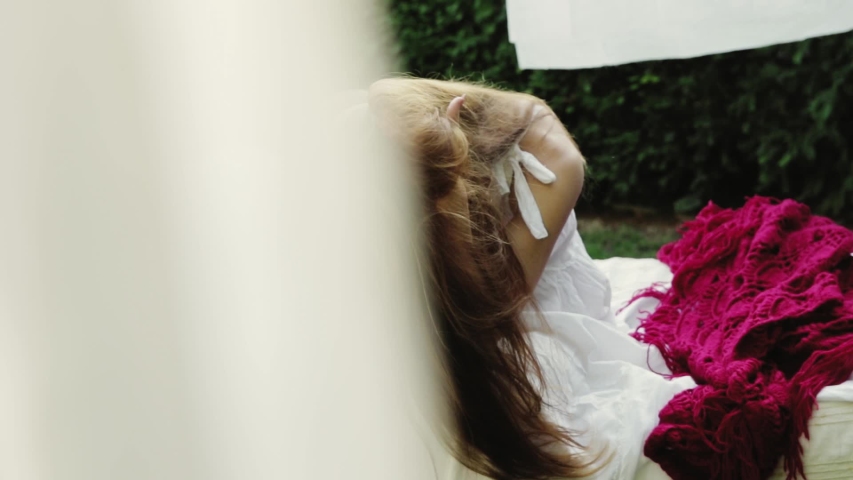girl is sorting hair sitting on a bed in the street
