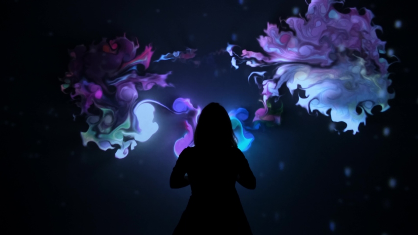 Girl plays with interactive video installation, New art form, generative graphics. Silhouette of girl draws multi-colored paints interactive installation. Woman does concept art with augmented reality Royalty-Free Stock Footage #1050086353