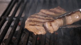 Two juicy steaks of meat with Golden crust and strips from grill BBQ are prepared on an open flame of barbecue grill, cook turns meat with metal tongs pork tenderloin. Dolly sliding video.