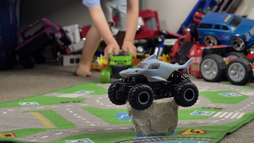 Little boy playing with toy truck car in his room alone. Child playing with toys (cars, trucks) indoor. Activities for kids at home