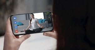 Professional fitness instructor teaching her client, how to do yoga exercises, during video chat on smartphone. Remote workout during quarantine time. Health care concept.