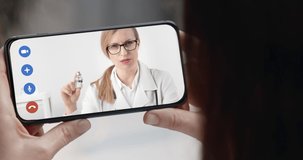 Mature lady sitting at home and having video chat with professional doctor that talking about coronavirus. Close up of smartphone screen. Concept of health care and awareness.