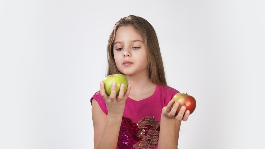 Girl with an Apple. Little girl eating an Apple Girl in a pink bright dress on a white background.