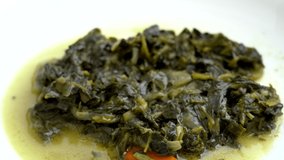 Closeup view video of white plate full of cooked hot spinach