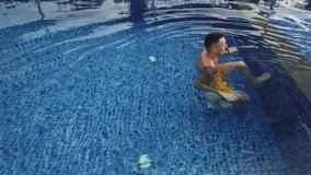Tattooed man swims in blue pool