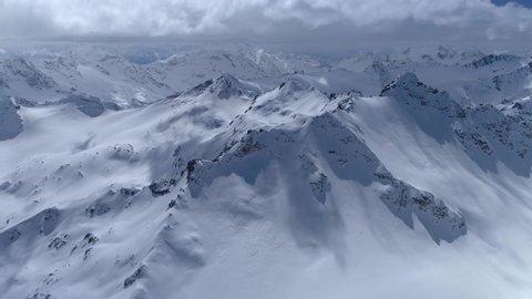 From great heigh fairytale mountain landscape snow covered alpine sharp peaks. Wild winter untouched inaccessible nature Russia Switzerland Alps abstract. Thick white clouds. Open space. Aerial 4K