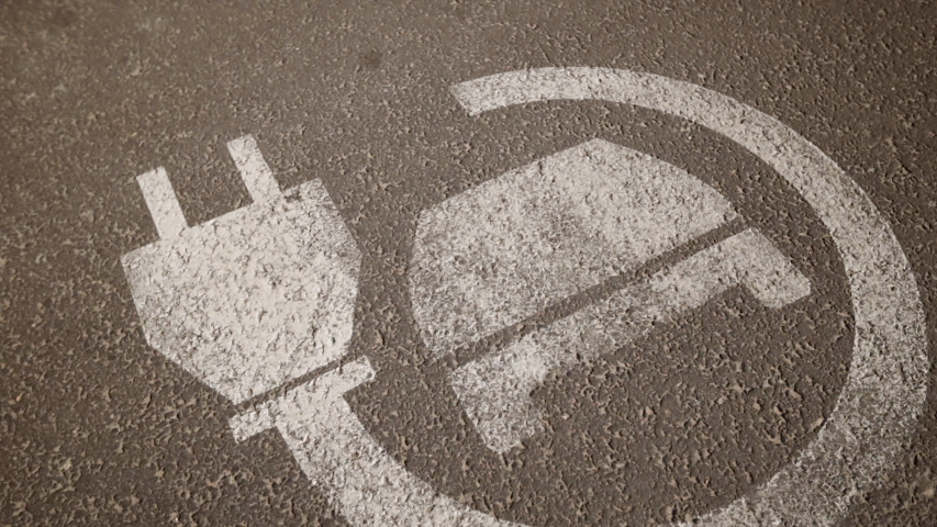 Close view of electric charger sign at asphalt parking lot near shopping centre or mall