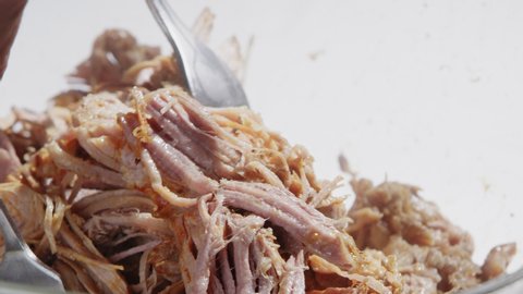 Mixing shredded pork with two forks