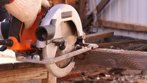  Circular saw in the process of operation. The carpenter cuts off the edges of a large piece of wood. Home workshop.  Work at home.