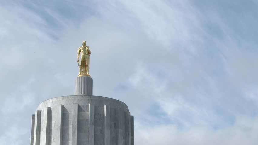 Salem, Oregon capitol building pioneer man statue with black bird flying by.