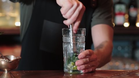 the process of making lime, mint and ice cocktail, mix the cocktail with a spoon. Close up of an experienced bartender who makes Mojito cocktails with lime, mint