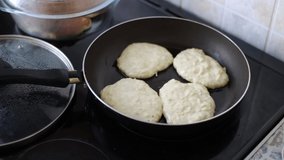 Video footage, female hands lay dough and fry pancakes in a pan on the stove