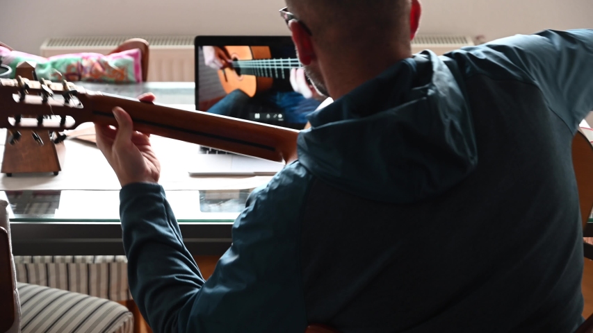 Man playing guitar at home. Man taking music lessons at home