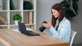 Work from home. The freelancer. 
A girl photographer processes photos on a laptop, then picks up the camera in her hands and reviews photos and smiling - Powered by Shutterstock - Get 15% off with code: PIKWIZARD15