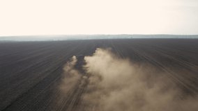 Spring field work, a tractor with a mounted seeder sow seeds in the ground on an agricultural field. aerial video