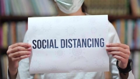 Social Distance to prevent covid-19 spread campaign, text on paper holding by women wearing mask, social distancing concept
