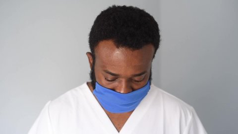 Black african american doctor wearing a white shirt and face mask to protect himself. 